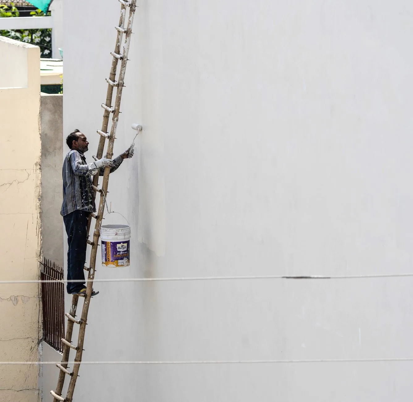 Peintre appliquant la peinture au rouleau sur perche pour peindre un plafond sans traces